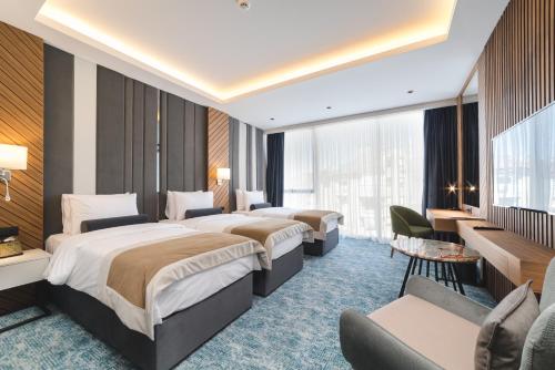 um quarto de hotel com três camas e uma secretária em Bristol Hotel Podgorica em Podgorica