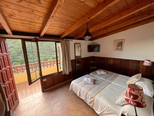 a bedroom with a bed and a large window at Hotel Rural Villa de Hermigua in Hermigua