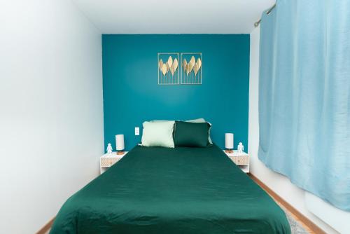 sypialnia z zielonym łóżkiem z niebieską ścianą w obiekcie Le Paradis Bleu w Lourdes