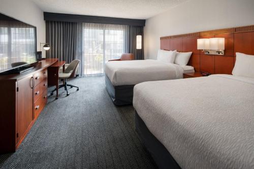 フレズノにあるCourtyard by Marriott Fresnoのベッド2台とデスクが備わるホテルルームです。