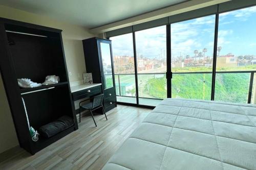 um quarto com uma cama, uma secretária e janelas amplas em Luxury 2BR Condo Rosarito (D) em Rosarito