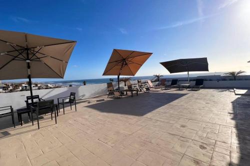 a patio with tables and chairs and umbrellas at Luxury 2BR Condo Rosarito (D) in Rosarito