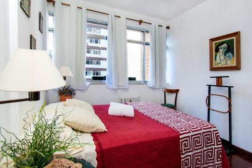 1 dormitorio con 1 cama roja y 2 ventanas en Caminhe para a Praia de Ipanema e para a Rua Farme de Amoedo, 2 quartos, todo reformado, ar, WI FI, en Río de Janeiro