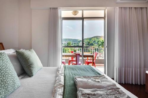 um quarto com uma cama e uma varanda com uma mesa em Jacarepaguá Residence - Quarto em apartamento no Rio de Janeiro