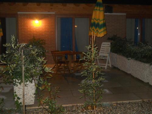 a patio with an umbrella and a table and chairs at Agriturismo La Palazzina in Castelnuovo del Garda