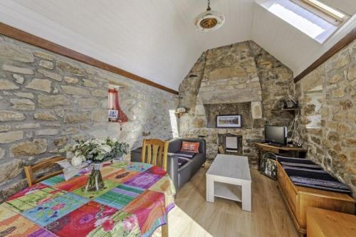 Cette chambre est dotée d'un mur en pierre avec un lit et une table. dans l'établissement Stone House in Plouarzel near Sandy Beaches, à Plouarzel