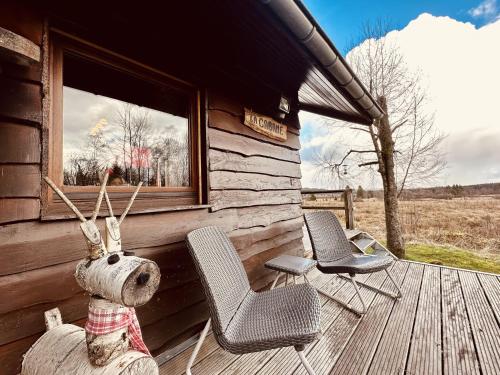 eine Hütte mit zwei Stühlen und einem ausgestopften Tier auf einem Deck in der Unterkunft Rustic Chalet ultimate relaxation in the forest in Sourbrodt