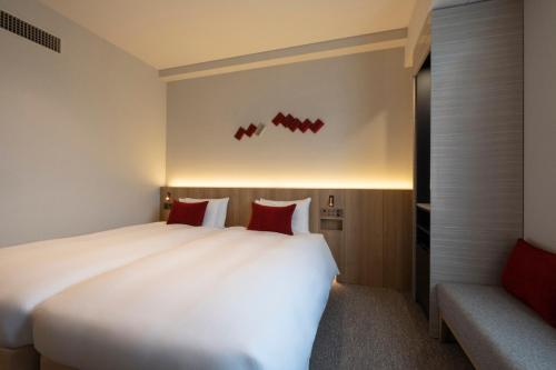 a bedroom with a large white bed with red pillows at Hotel JAL City Haneda Tokyo in Tokyo