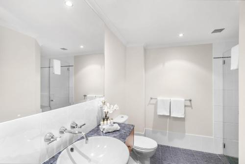 a white bathroom with a sink and a toilet at Belle Escapes Poolside Ground Floor Suite 41 Alamanda Palm Cove in Palm Cove