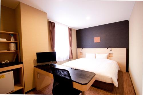 a bedroom with a bed and a desk with a computer at Smile Hotel Otsu Seta in Otsu