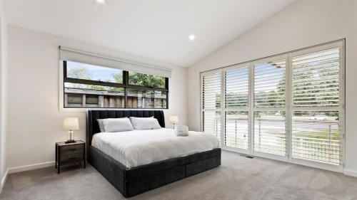 a white bedroom with a bed and large windows at Villa Marina in Lakes Entrance