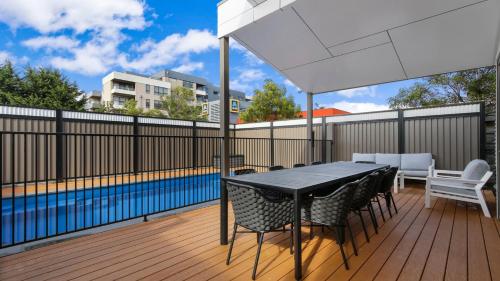 a patio with a table and chairs and a swimming pool at Villa Marina - Modern Waterfront Escape in Lakes Entrance