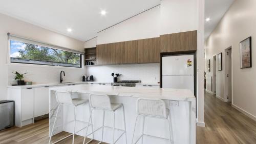 a kitchen with a large white island with stools at Villa Marina - Modern Waterfront Escape in Lakes Entrance