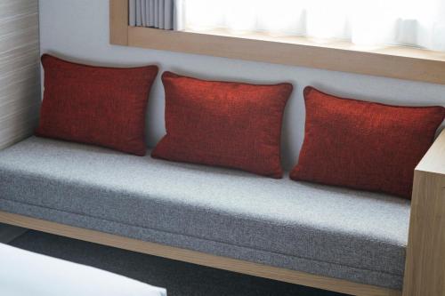 two red pillows sitting on a bench under a window at Hotel JAL City Haneda Tokyo in Tokyo