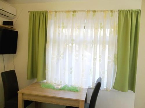 a room with a table and a window with green curtains at Apartment Vrančić in Šibenik