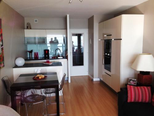 Il comprend une cuisine et un salon avec une petite table et des chaises. dans l'établissement Appartement T2 refait à neuf avec balcon face mer et ascenseur, au cœur des Sables-d'Olonne - FR-1-485-70, à Les Sables-dʼOlonne