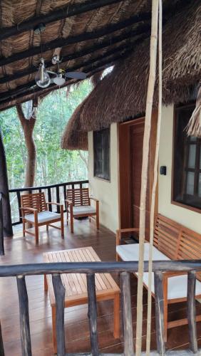 a porch of a house with benches and a thatch roof at Hotel Cabañas Aldea Maya in Xpujil