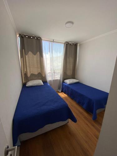 Habitación pequeña con 2 camas y ventana en DEPARTAMENTO CENTRICO, en Iquique