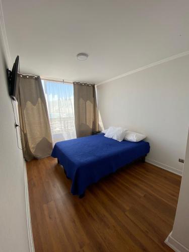 1 dormitorio con 1 cama azul en una habitación con suelo de madera en DEPARTAMENTO CENTRICO, en Iquique