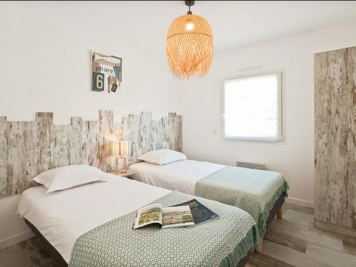 2 łóżka w pokoju z białymi ścianami i żyrandolem w obiekcie Villa Les Sables-d'Olonne, 4 pièces, 6 personnes - FR-1-485-115 w mieście Les Sables-dʼOlonne