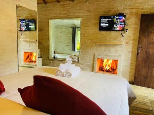 a bedroom with a large bed with a fireplace at Chalé Recanto dos Pinheiros in Monte Verde