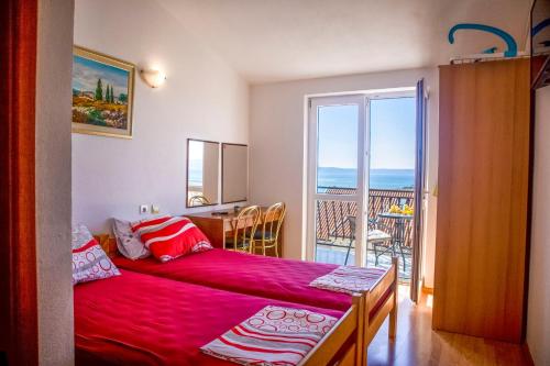a bedroom with a red bed and a balcony at Apartments Julijana in Makarska