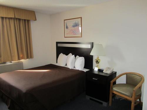 a hotel room with a bed and a chair and a phone at Super 8 by Wyndham Williams Lake BC in Williams Lake