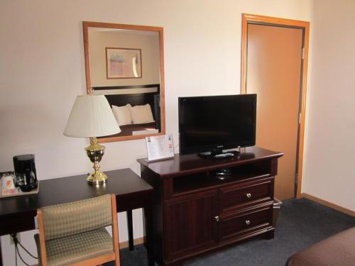 a hotel room with a desk and a television on a dresser at Super 8 by Wyndham Williams Lake BC in Williams Lake