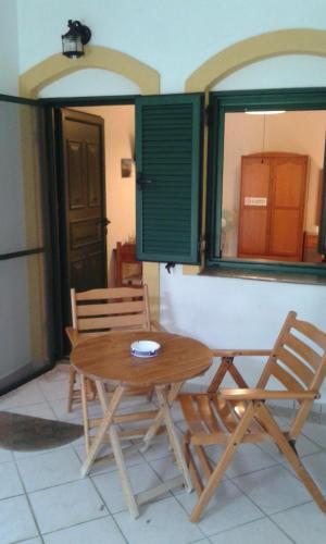 a wooden table and two chairs next to a window at Evon's Rooms in Fanari