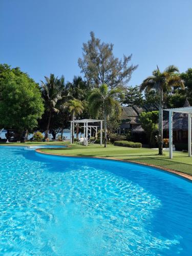 een zwembad met blauw water en bomen bij Phayam Cottage Resort in Ko Phayam