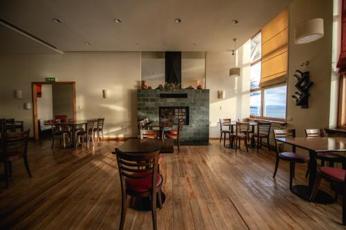 um restaurante com mesas e cadeiras e uma lareira em Hosteria Kaiken em Tolhuin