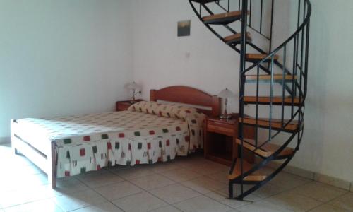a bedroom with a bed and a spiral staircase at Evon's Rooms in Fanari