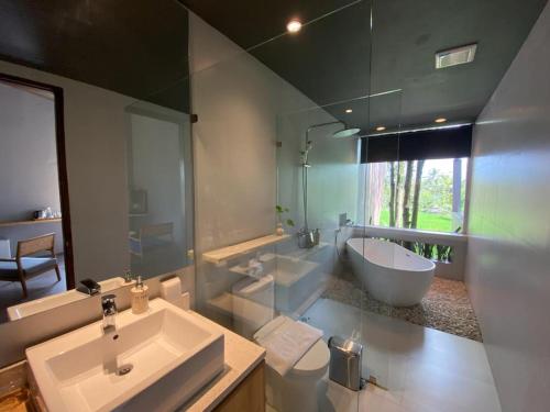 a bathroom with a sink and a tub and a toilet at Teras Hotel Ijen Banyuwangi in Banyuwangi