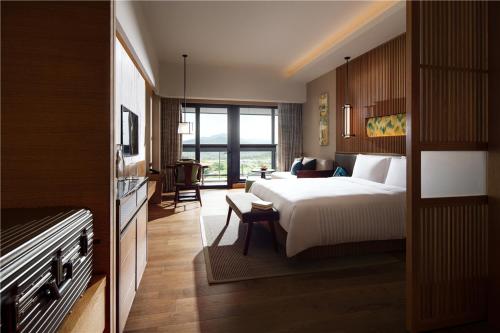 a bedroom with a large bed and a living room at New World Qingyuan Hotel -formerly KHOS QINGYUAN in Qingyuan
