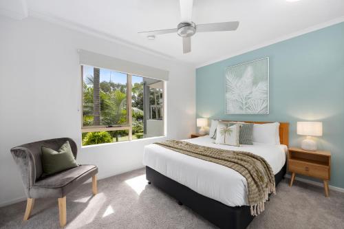 a bedroom with a large bed and a chair at Como Noosa in Noosaville