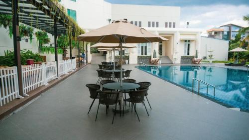 a patio with tables and chairs and a swimming pool at Emerald Garden International Hotel in Medan