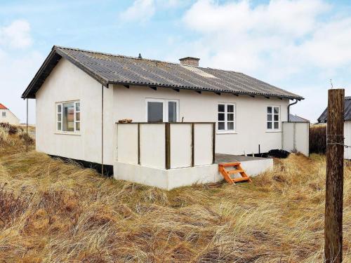 a small white house on a hill in a field at 4 person holiday home in Frøstrup in Frøstrup