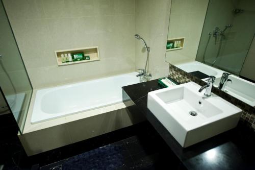 a bathroom with a white sink and a bath tub at Emerald Garden International Hotel in Medan