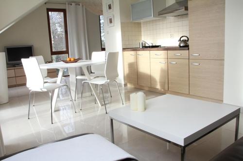 a kitchen with a white table and white chairs at Apartament Morski in Rewal