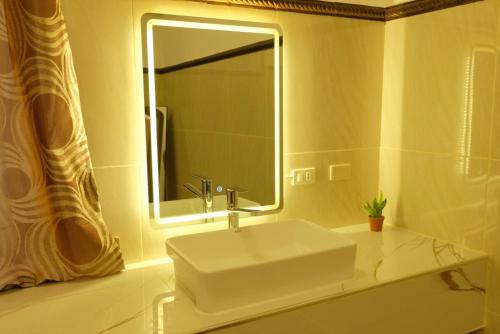 y baño con lavabo blanco y espejo. en Villa Italia Hotel en Sorsogon