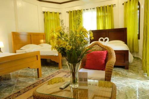 a room with two beds and a table with a vase of flowers at Villa Italia Hotel in Sorsogon