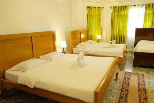 two beds in a hotel room with green curtains at Villa Italia Hotel in Sorsogon