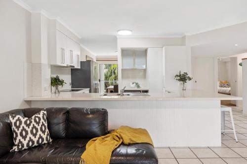 a living room with a couch and a kitchen at Sunset Cove Noosa in Noosaville