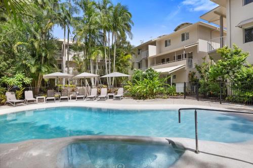 a swimming pool with chairs and a building at Sunset Cove Noosa in Noosaville