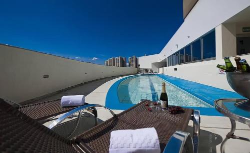 uma piscina com uma mesa e uma garrafa de vinho em Unidade Executiva Luxo 33m² em Brasília