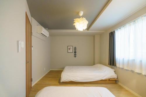 - une chambre avec 2 lits et une fenêtre dans l'établissement 自由自在OSU 402(KUMO), à Nagoya
