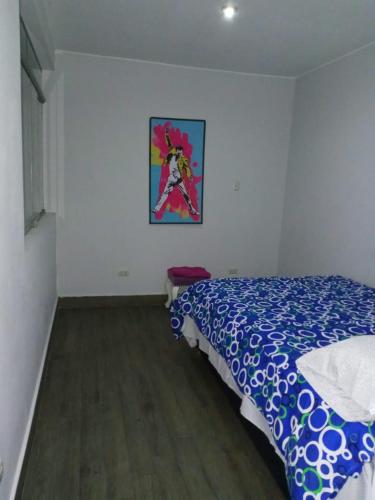 1 dormitorio con 1 cama y una pintura en la pared en Los condores La Molina, en La Molina