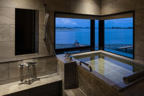 a bathroom with a tub with a view of the water at Matsushima Ichinobo in Matsushima