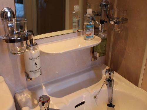 a bathroom sink with bottles of soap and a mirror at Highfield Guest House in Edinburgh