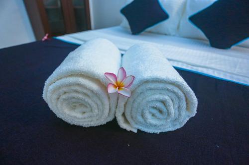 un rollo de toalla con una flor en la cama en Villa 382, en Galle